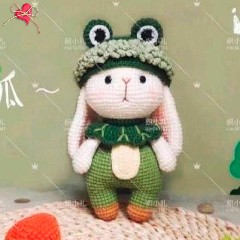Мягкая вязаная игрушка-заяц с забавной шапкой-лягушкой и яркими градиентными ногами, идеально подходящая для уютных обниманий и украшения детской комнаты.0