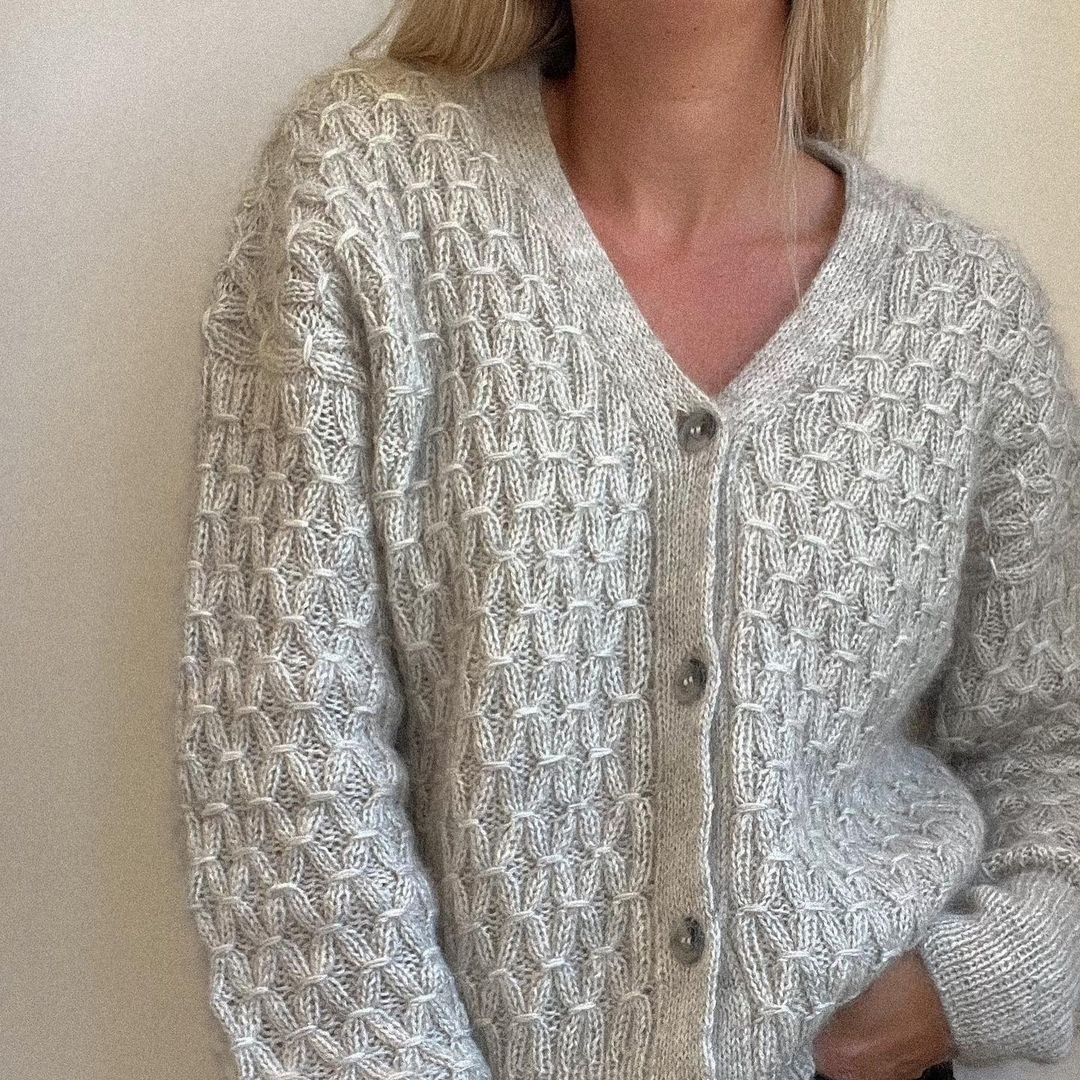 Уютный вязаный кардиган с крупной текстурой и контрастными пуговицами, напоминающими старинные деревянные бусы.1