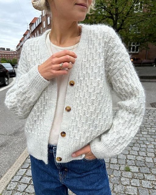 Уютный вязаный кардиган с крупной текстурой и контрастными пуговицами, напоминающими старинные деревянные бусы.0